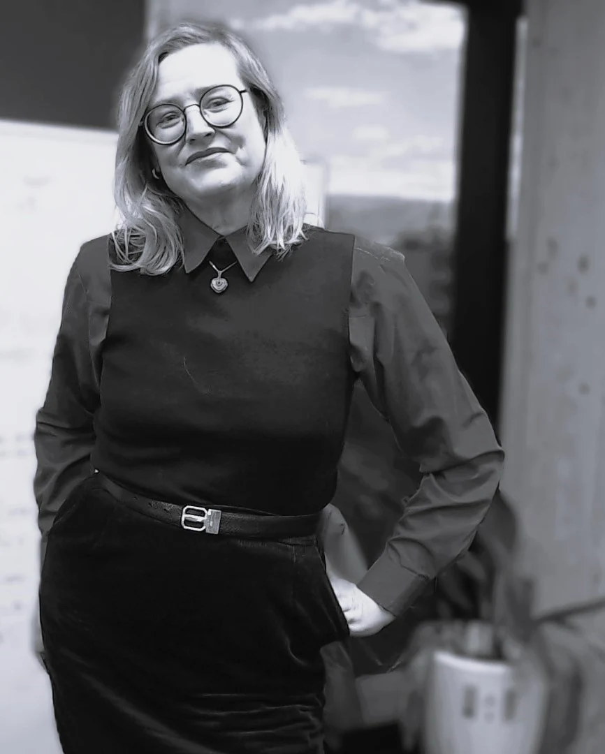 Black and white portrait photograph of Penny Maxwell, founder of Maxwell Minds, standing in the clinic
