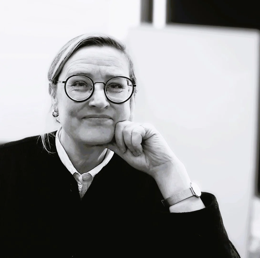 Black and white portrait photograph of Penny Maxwell, founder of Maxwell Minds, resting her chin on her hand and smiling